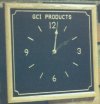 GCI PRODUCTS BLACK GRANITE 4 NUMBER CLOCK WITH GOLD COLOR INLAY AND GOLD COLOR SQUARE BORDER WITH CONCAVE CORNERS IN LIGHT OAK FRAME.